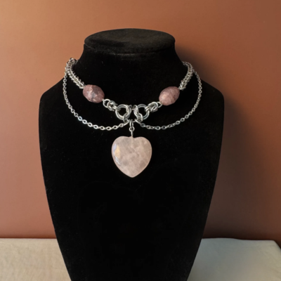 Rose quartz choker necklace with a heart centerpiece and strawberry quartz accents. Romantic, bold, and designed with a soft drape and structured form.