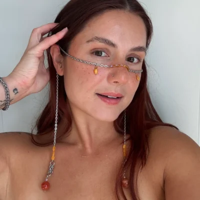 Chainmail face chain with orange gemstone beads worn across the face